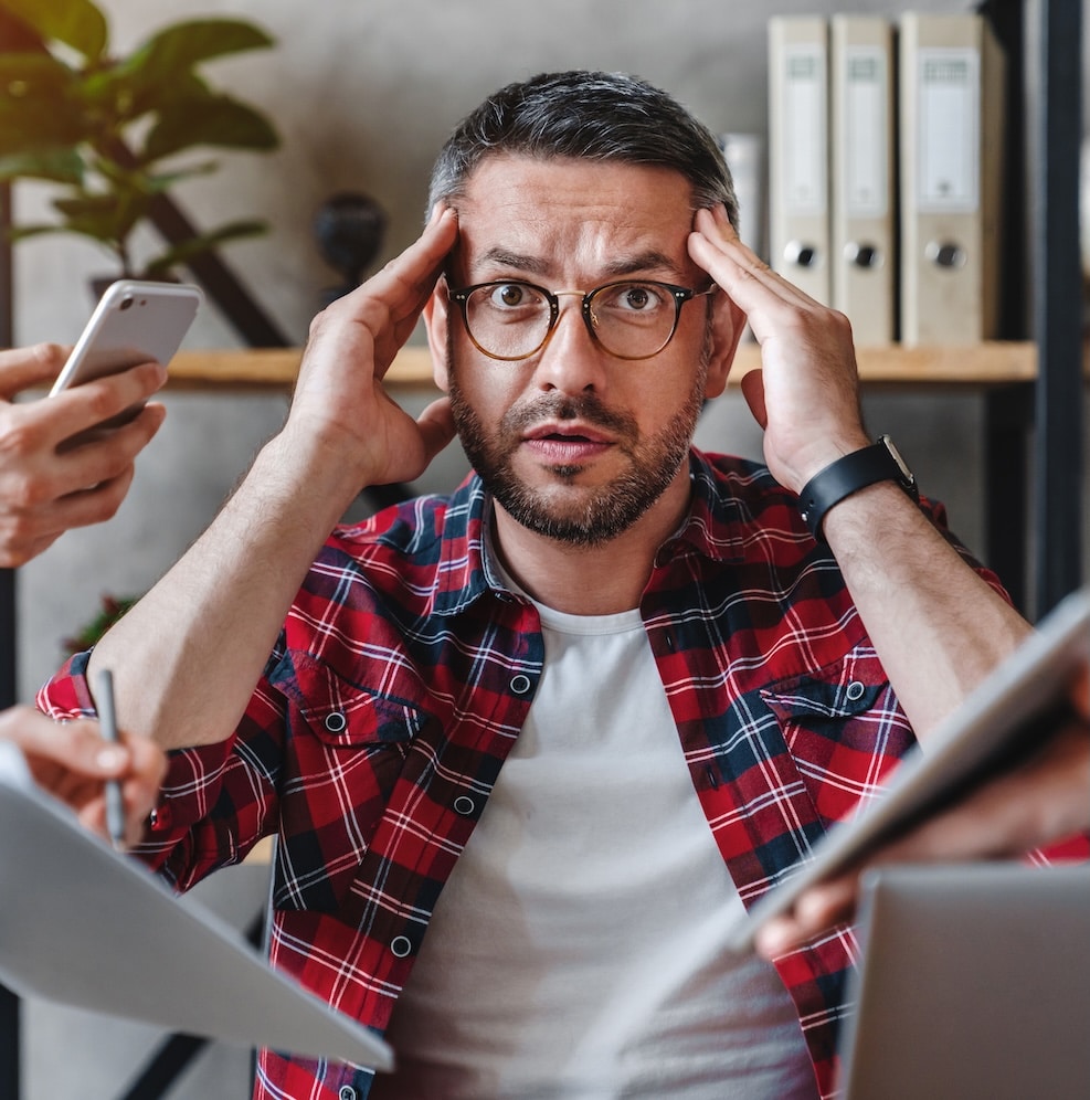 Overworked businessman sitting at laptop overloaded with work multiple tasks in modern office